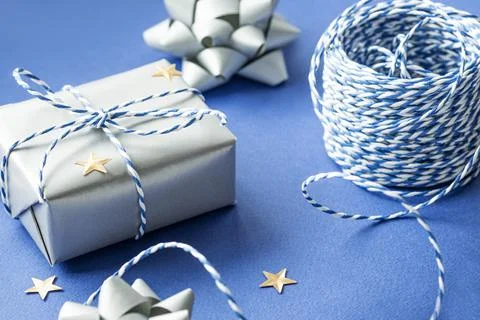 Gift packaging: silver bows for gift decoration, blue gift rope, gift in a wh Stock Photos