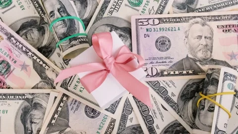 Gift present on money dollar background rotating, spinning. Buying gifts for Stock Footage 154710277