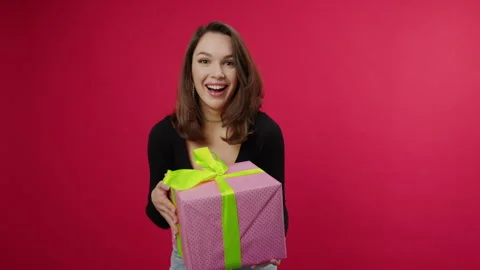 A gift on a red background falls into the hands of a young woman from above Stock Footage 249798605