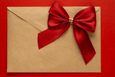 Gift red bow on a craft envelope on textured red background Stock-Fotos
