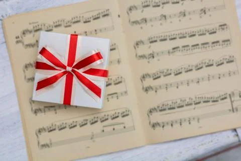Gift with red bow lying on sheet music Stock Photos