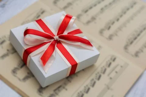 Gift with red bow lying on sheet music Stock Photos