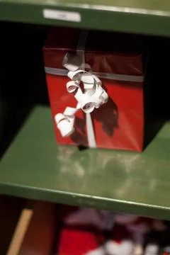 Gift in a red box with a white ribbon on a green shelf Stock Photos