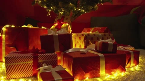 Gift red packages with ribbons under a green tree. Slow motion. Stock Footage 225688080