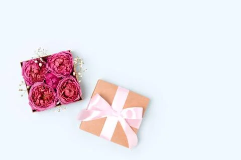 Gift with a tied bow. Open box with rose flowers inside. Stock Photos