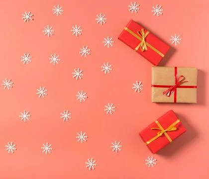 Gift-wrapped boxes and lots of white snowflakes on red background Stock Photos