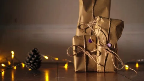 Gift wrapped in brown paper and string with Christmas lights bokeh background Stock Footage 297777216