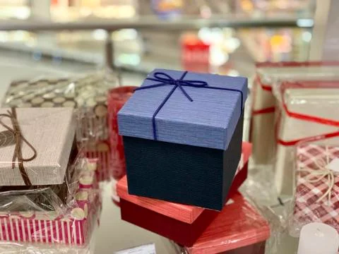 A gift wrapped in a square box with a ribbon on the background of other gifts 写真素材