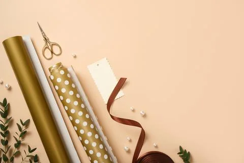 Gift wrapping background. Paper rolls, gift tag, and pearls on beige desk. .. 스톡 사진