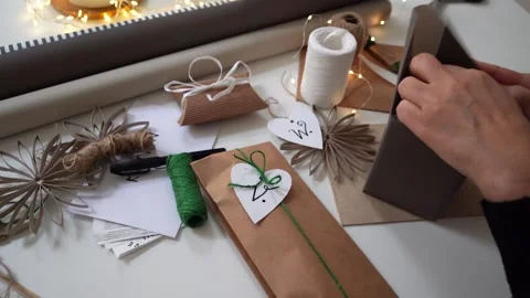 Gift wrapping with dark grey paper and white ribbon for Christmas by woman Stock Footage 292866748