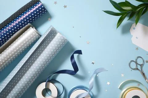 Gift wrapping flat lay with blue and polka dot paper, scissors, a blank tag,  库存照片