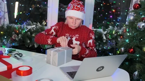Gift wrapping following tutorial on internet, prepares for party Christmas Stock Footage 255849500