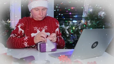 Gift wrapping following tutorial on internet, woman in red sweater with reindeer 動画素材 287298765