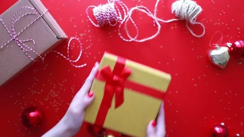 Gift wrapping. Hands put a box with a red bow. Christmas flat lay Stock Footage 245363572