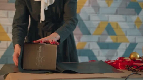 Gift wrapping scene. Festive gift wrapping with decorative ornaments and careful Stock Footage 345168295