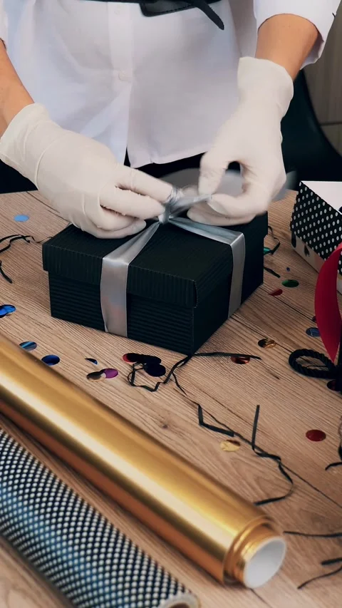 Gifts wrapping close-up. Top view. Designer, in protective gloves, decorates, Stock Footage 323079288