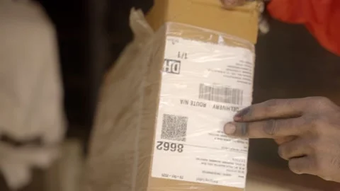Gig worker scanning QR code of packed parcel at logistic warehouse Stock Footage 327630227