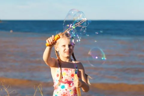 Gilrl with soap bubbles on the seashore Stock Photos