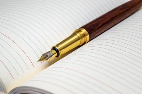 Gilt pen rests on open notebook for notes or writing a text Stock Photos
