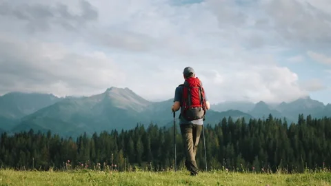 Gimbal shot man with backpack walking green grass meadow hill mountain landscape Stock Footage 283024866