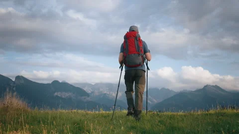 Gimbal shot man with backpack walking green grass meadow hill mountain landscape Stock Footage 283025349