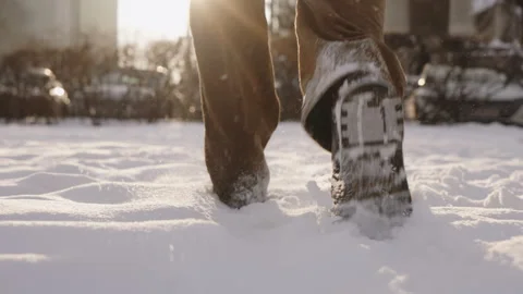 Gimbal shot of man walking through deep fresh snow on sunny winter day in city Stock Footage 326826486