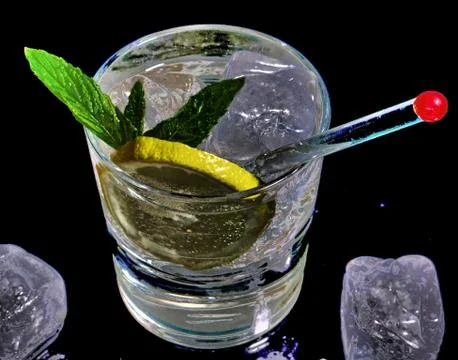 Gin and tonic  with slice of yellow lemon and red head glass stick. Stock Photos