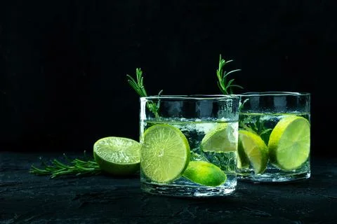 Gin tonic glasses, side view with rosemary and lime. Fresh summer cocktail Stock Photos