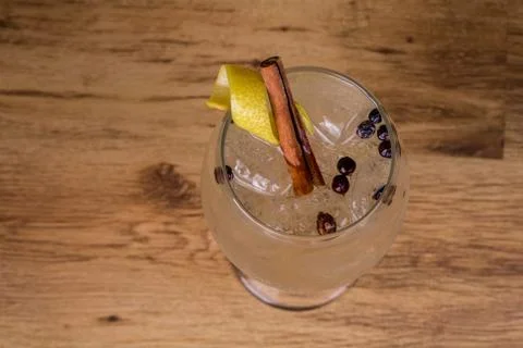 Gin tonic with lemon slice, cinnamon sticks and juniper. At thewood backgroun Stock Photos