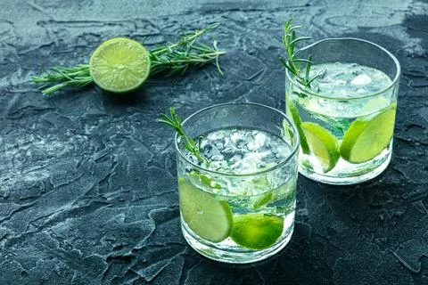 Gin tonic, two glasses of gin with soda, lime, rosemary, and plenty of ice Stock Photos