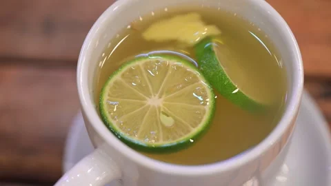 Ginger and lime slices floating in a cup of tea Vídeo Stock 311874930