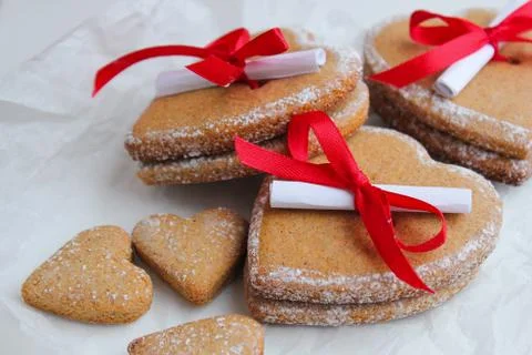 Ginger biscuits in the shape of a heart with a note and a red bow Stock Photos