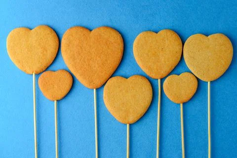Ginger biscuits on a stick in the form of hearts on a blue background Stock Photos