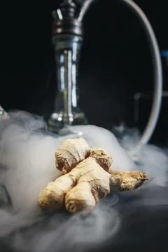Ginger on black background. In the background are hookah and smoke. Foto stock