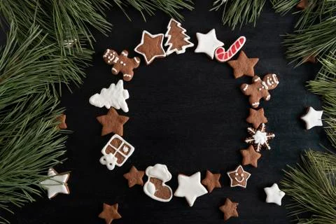Ginger bread cookies in circle form on black background and spruce branches.  Stock Photos