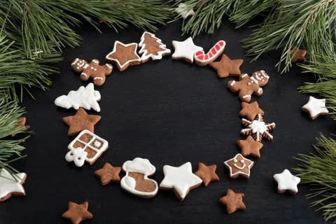 Ginger bread cookies in circle form on black background, spruce branches. Cop Stock Photos