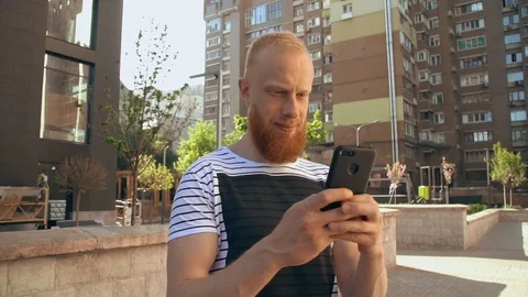 Ginger guy scrolling touch screen phone Stock Footage 90711914