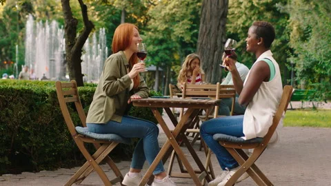 A ginger haired lady with her african friend are sipping on wine and feeling Stock Footage 160976804