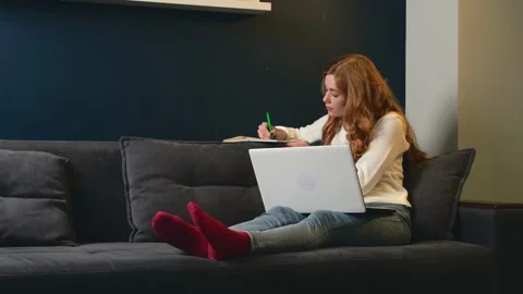 Ginger lady is busy because of doing online classes and writing topic using a Stock Footage 146212166
