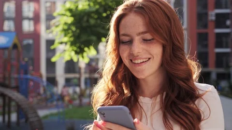 Ginger lady using mobile phone for browsing social media outdoors city square. 스톡 동영상 159978344