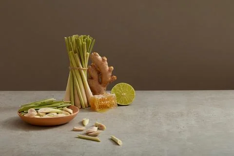 A ginger, a lemon slice and many lemongrass are displayed on minimalist backg Stock Photos