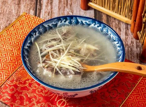 Ginger mutton clear soup with spoon served in bowl isolated on napkin side .. Stock Photos