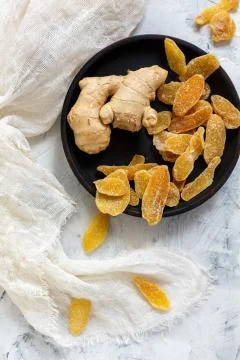 Ginger root and candied ginger on a wooden plate. Stock Photos