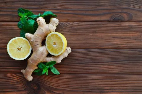 Ginger root, lemon halves, and mint leaves on wooden surface. A fresh Stock Photos