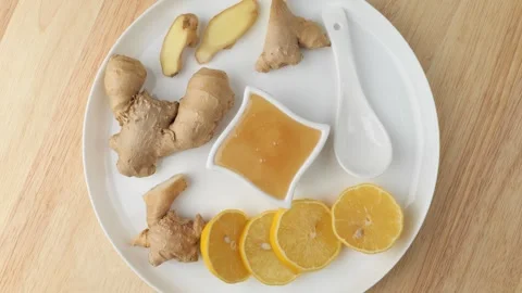 Ginger root, lemon slices, and honey rotating on a plate Stock Footage 347099636