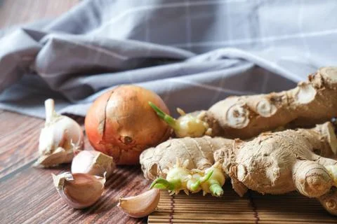 Ginger root, onion and garlic with wooden texture background Stock Photos