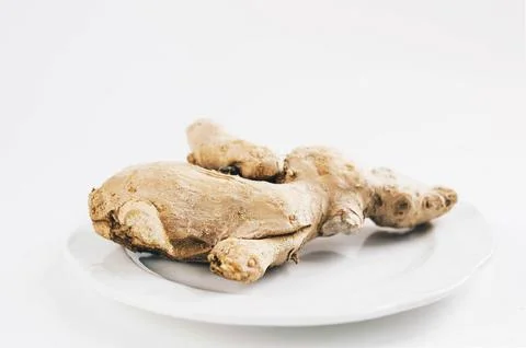 Ginger root in a plate on white background Stock Photos