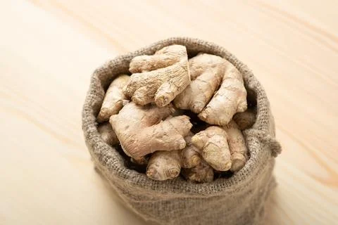 Ginger root in small bag against wooden table Stock Photos