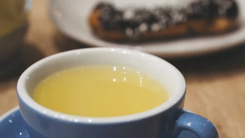 Ginger tea and chocolate eclair on the table in a cafe. Stock Footage 86698425