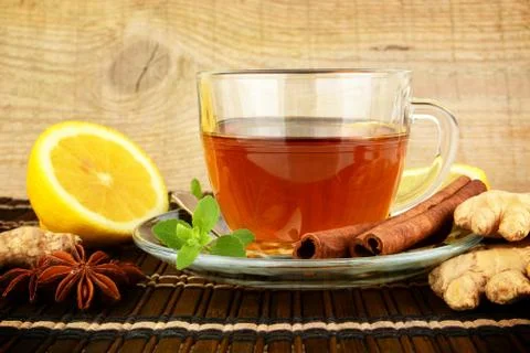 Ginger tea-ingwertee on brown mat with lemon,cinnamon,anise and mint on mat Stock Photos